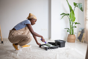 African American woman spreading paint on roller