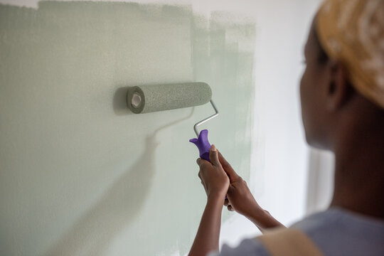 Black painter holding roller with both hands