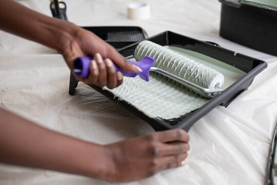 Crop black woman taking green paint from tray