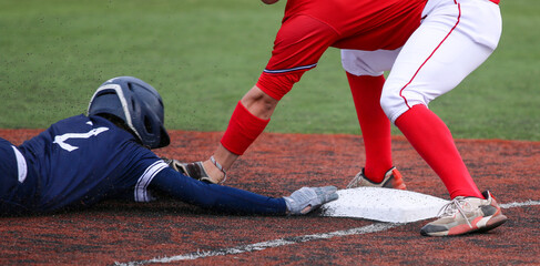 Third baseman tagging out runner who is head first sliding