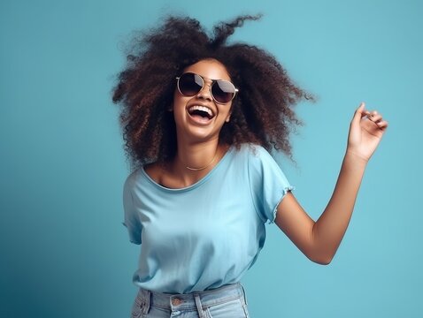 Gl&uuml;ckliche Frau mit Afrolocken tanzt in l&auml;ssigem T-Shirt und Sonnenbrille auf blauem Hintergrund, generative AI.