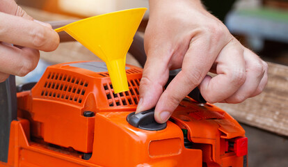 Unscrewing the cap of the fuel tank of the chainsaw for refueling a mixture of gasoline with...
