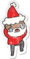 distressed sticker cartoon of a bearded man crying and stamping foot wearing santa hat