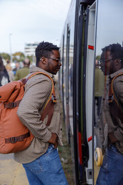 Man with backpack getting into tram at station