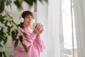 elderly woman listening to music or a podcast by a window, reflecting on the complexities of aging and the impact it has on our emotional wellbeing.