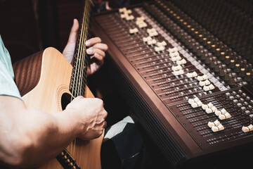 close up male musician, composer playing acoustic guitar in studio. acoustic musical instrument recording or songwriting concept