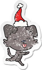 distressed sticker cartoon of a dog sticking out tongue wearing santa hat