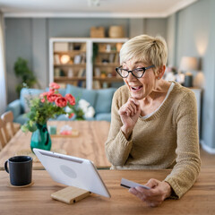 Senior woman caucasian female hold credit card online shopping at home