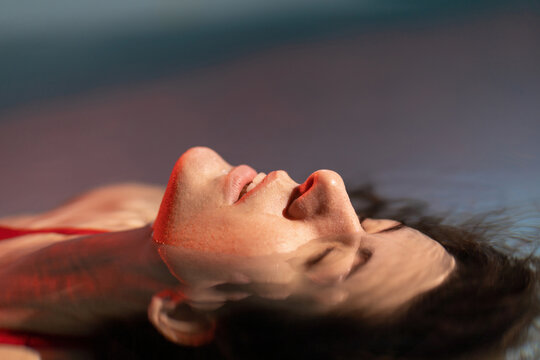 Graceful lady in scarlet dress posing in water