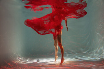 Graceful lady in scarlet dress posing underwater