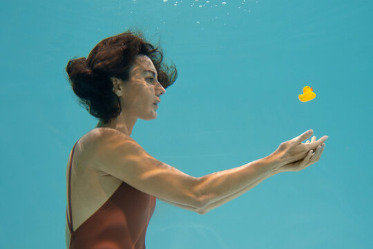 Brunette model posing underwater with toy duck