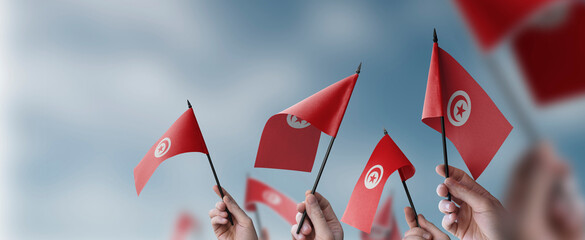 Fototapeta na wymiar A group of people holding small flags of the Tunisia in their hands