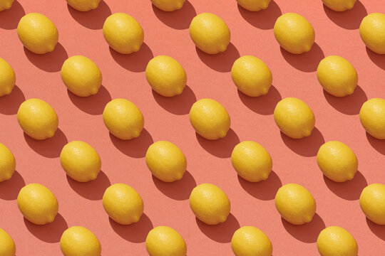 Many whole ripe yellow lemons on a seamless red background