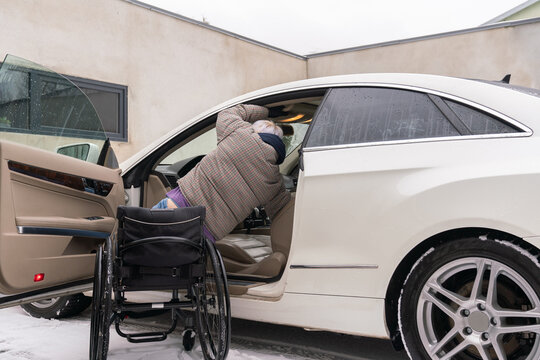 Woman In Wheelchair Entering In Her Car