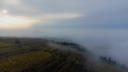 Aerial of the hills covered in the fog in Soave, Verona, Italy with the cloudy sky on background