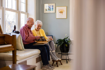 Casual Senior Citizen couple at home view at family photo album 