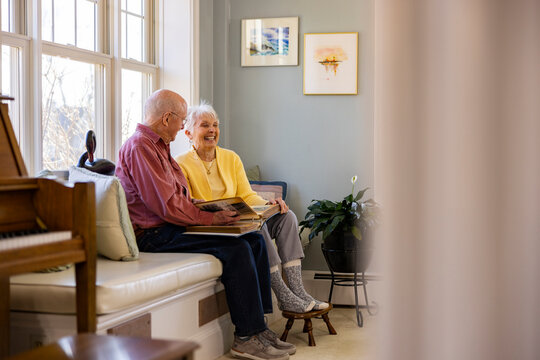 Leisure Senior Citizen couple at home laugh at family photo album 