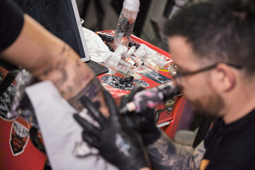 Tattoo of a lion on the arm of the client in the salon. Tattoo artist working on a client's arm in...