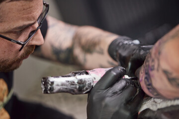 Tattoo of a lion on the arm of the client in the salon. Tattoo artist working on a client's arm in...