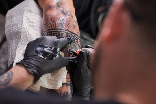 Tattoo of a lion on the arm of the client in the salon. Tattoo artist working on a client's arm in his studio.