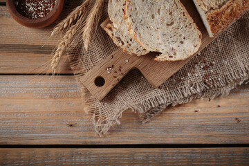 Sliced fresh baked whole grain bread with oats, flax seeds and sesame seeds on rustic wooden board. Bakery products