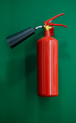 Red metal extinguisher on the green wall in corridor of the modern office