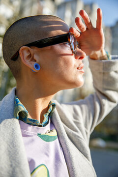 Young woman in sunglasses shielding eyes and looking faraway