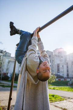 Crazy woman with bald head hanging from metal bars at park