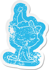 cartoon distressed sticker of a cat with bow on head wearing santa hat