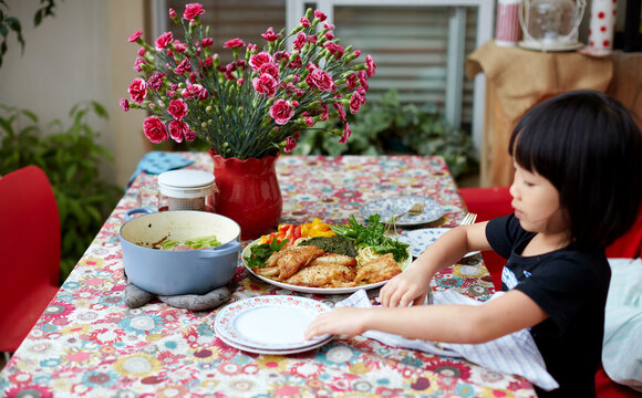 Asian girl fiddling with cutlery at the party table on the balcony