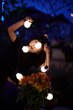 Asian little girl playing with decorative lighting on the balcony