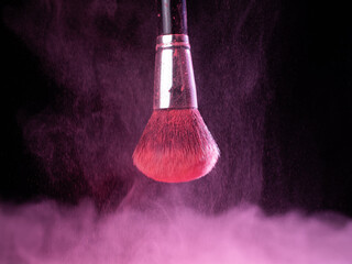 Fototapeta na wymiar Make-up brush with pink powder splashes explosion on black background. Beauty concept