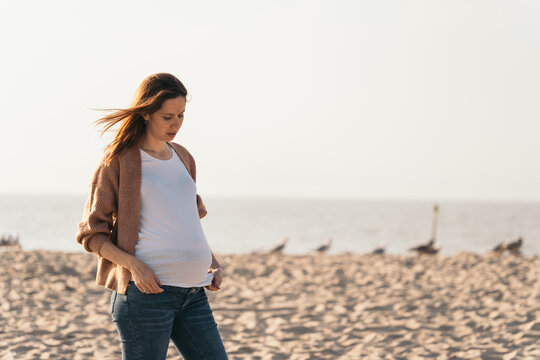 woman with her hair flying around looking at her pregnant bel