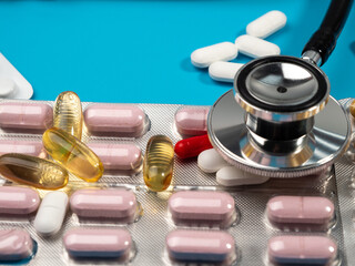 Pills and stethoscope on a blue background. Medicine concept. Close-up.