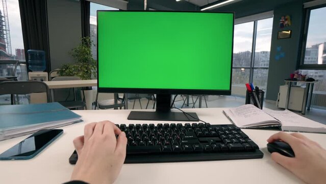 Handheld Camera: Point of View Of Young Girl Working At Computer With Green Mock Up Screen in Office. Desktop Computer With Mock Up Green Screen