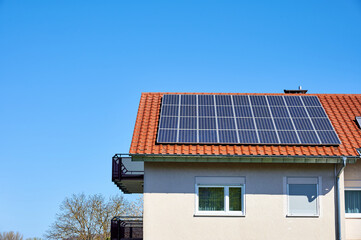 Solarzellen auf rotem Hausdach vor blauem Himmel