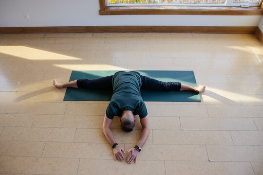 Flexible man doing yoga stretch in studio.