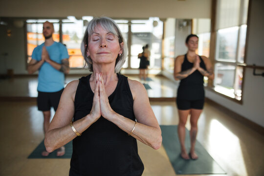 Meditative group yoga class practice inside modern studio.