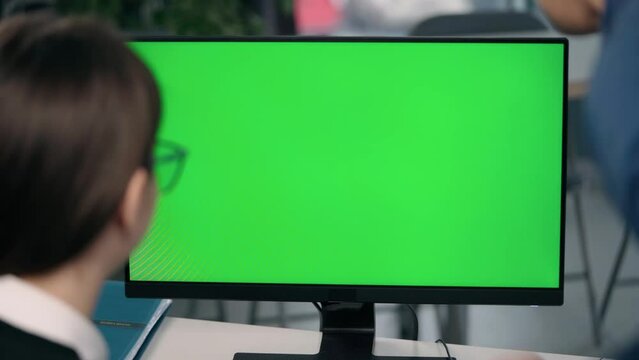 Young Woman Discusses Work Projects with Male Colleague by Showing Her Computer Monitor With Green Mock Up Screen In Office