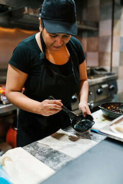 Female cook basting baking paper with oil