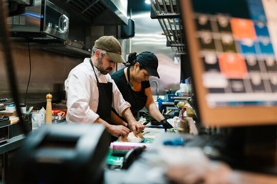 Colleagues preparing food in restaurant kitchen