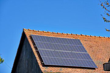 Scheunendach mit Solarzellen vor blauem Himmel