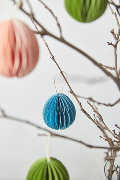 Colorful papercraft ornaments hung on branches.