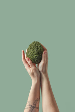 Crafted green Easter egg held by woman's hands.