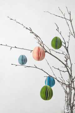 Handmade paper Easter eggs hung on branches.
