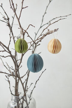Ornate papercraft Easter eggs hung on branches.