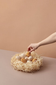 Wooden Easter eggs laid by woman's hand in nest.