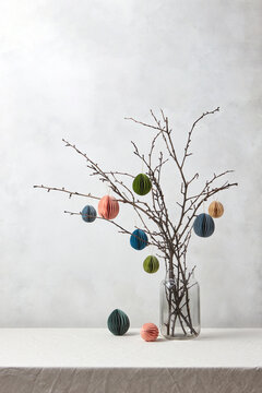 Colorful paper Easter eggs hung on tree branches.