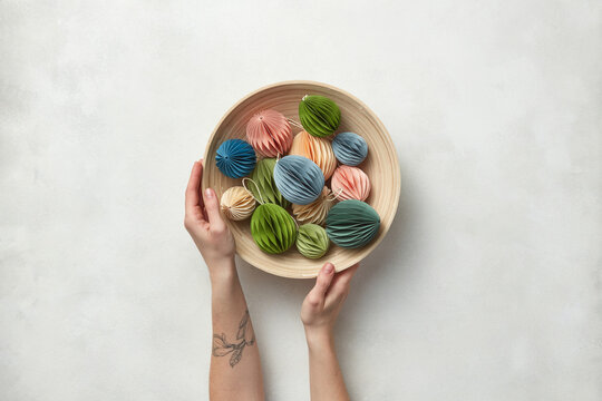 Papercraft ornaments in bowl held by woman.