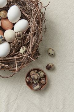 Quail eggs in bowl, chicken eggs in nest beside.